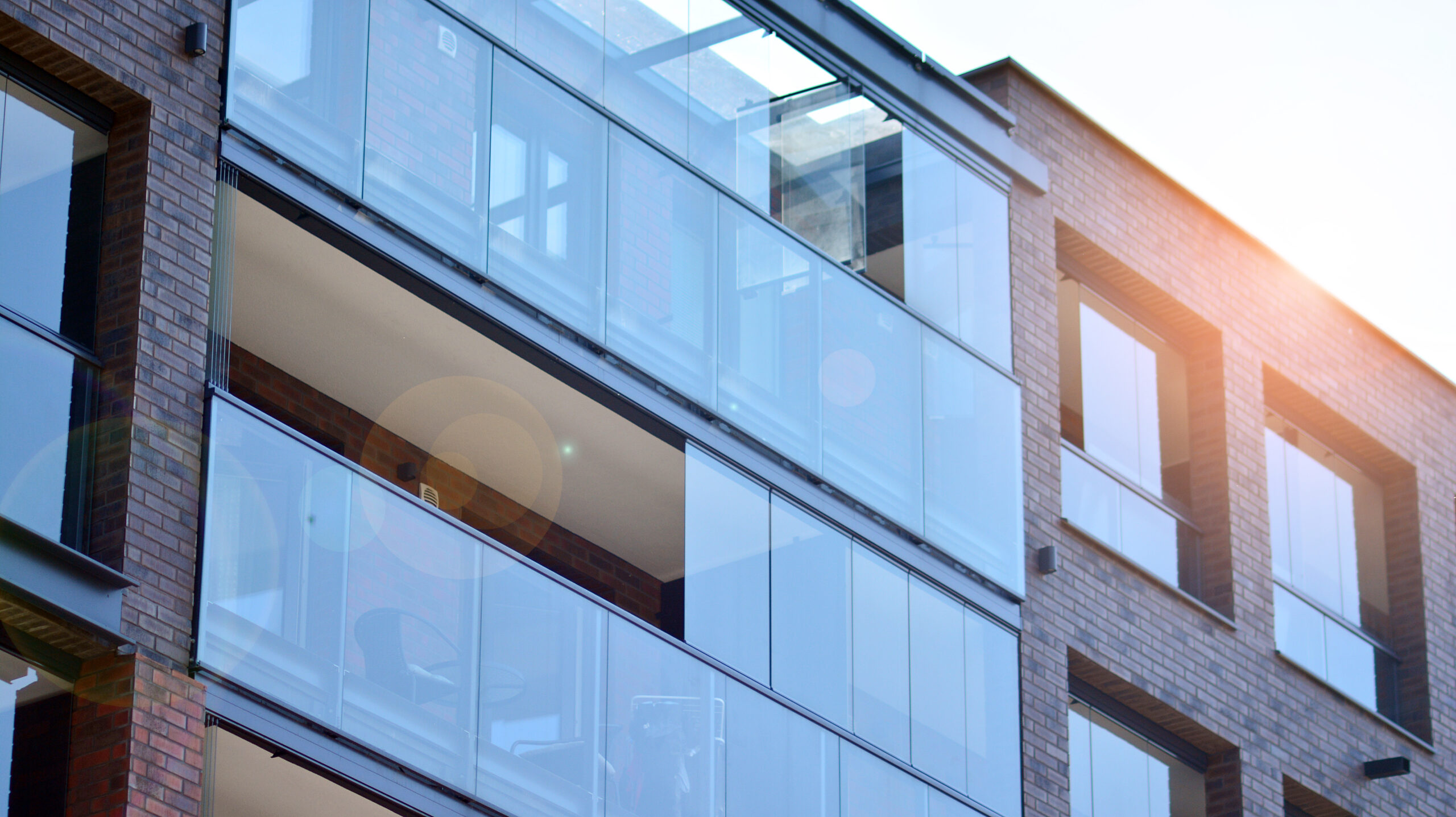 Панорамное фасадное остекление жилого дома с раздвижными стеклянными системами и солнечным отражением