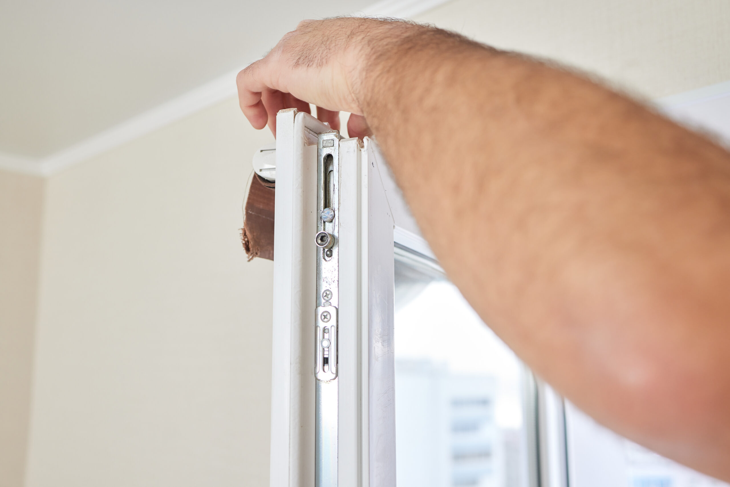 Мастер проверяет фурнитуру и регулировку пластикового окна